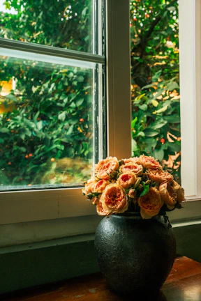 Charming arrangement of peach and cream roses on a wooden table with natural sunlight