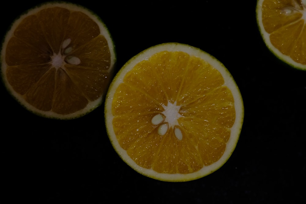 three oranges cut in half on a black surface