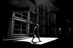 Artistic shot of a model walking down a city street wearing a slim fit grey t-shirt with subtle shadows