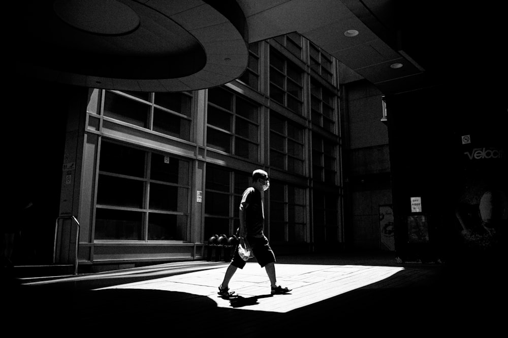 a man walking down a street next to a tall building