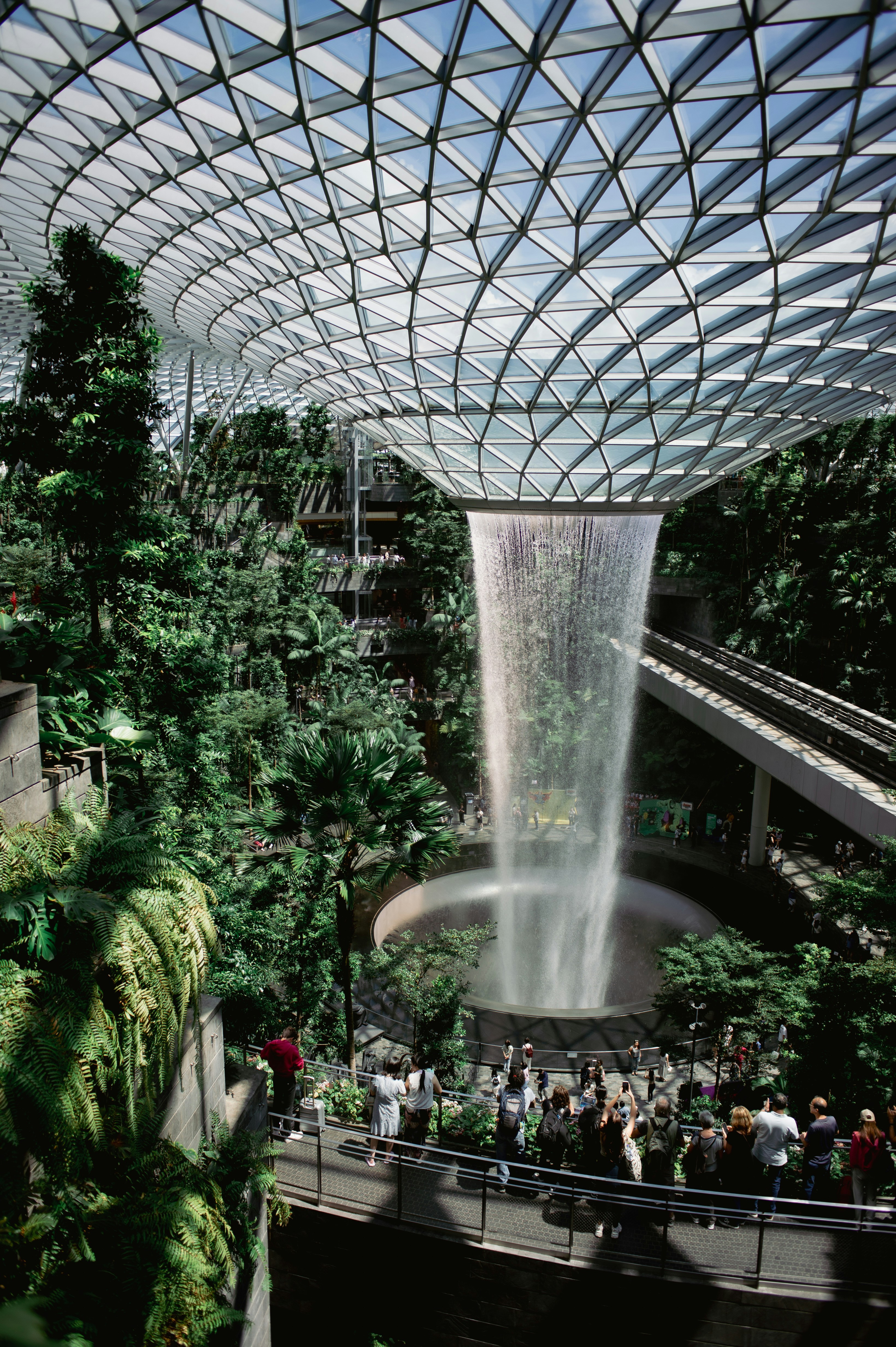 a group of people standing around a waterfall inside of a building