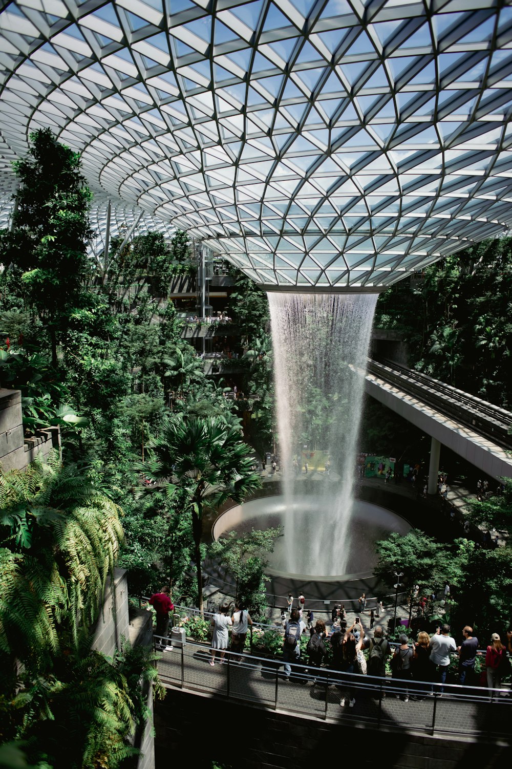 a group of people standing around a waterfall inside of a building