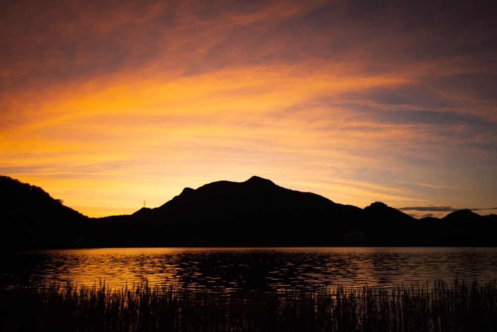 a sunset over a lake with mountains in the background