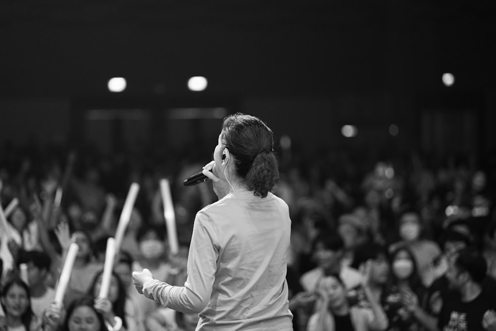 a woman standing in front of a crowd holding a microphone