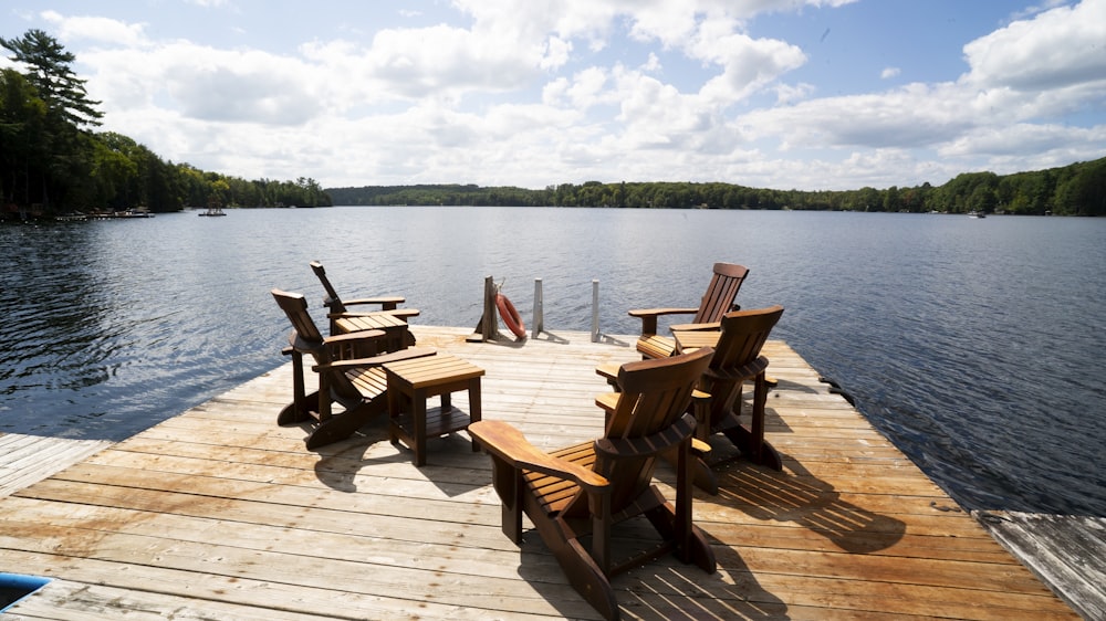 a dock with chairs on it next to a body of water