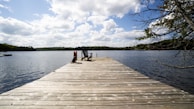 Peaceful lakeside dock with Adirondack chairs ready for a quiet afternoon.