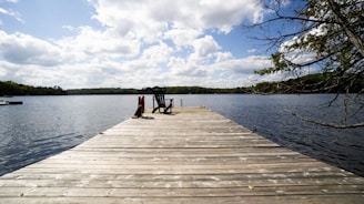 Peaceful lakeside dock with Adirondack chairs ready for a quiet afternoon.