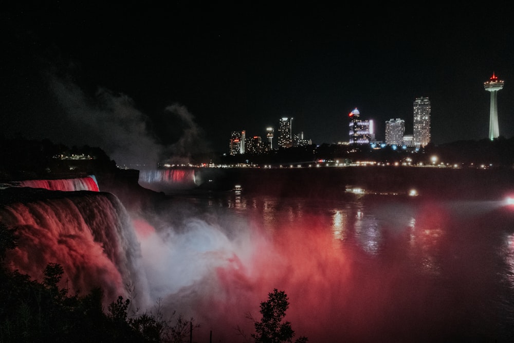 a view of niagara falls at night with the city lights in the background