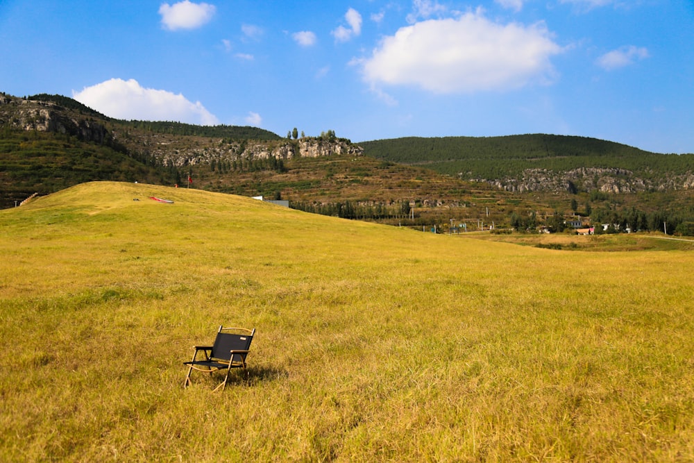 a lone chair in a field with mountains in the background