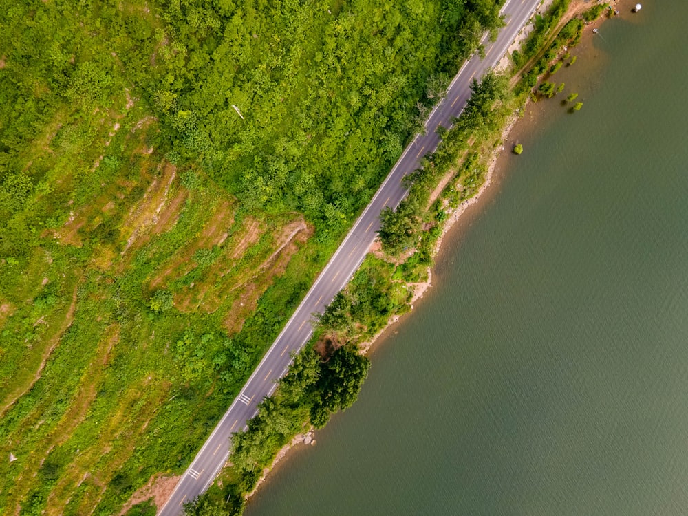 an aerial view of a road next to a body of water