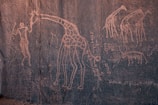 A group of safari travelers observing ancient rock paintings in Uganda.