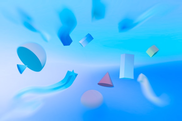 A collection of various geometric shapes floats against a soft, abstract background. The shapes, including spheres, cones, cylinders, and rectangles, appear to be suspended mid-air with a gradient of calming blues and pastel colors. The overall composition gives a sense of lightness and fluidity, as if the objects are gently drifting in a serene, surreal space.