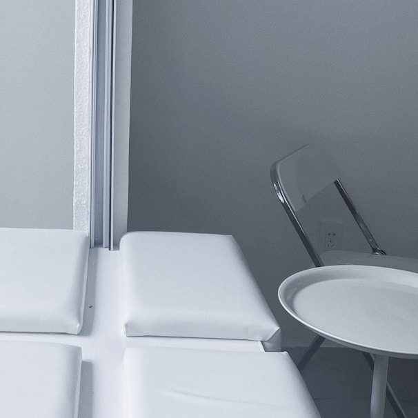 A sleek modern folding table neatly folded and leaning against a wall in a small apartment corner.