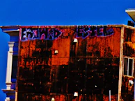 Exterior of a commercial building with a fresh coat of warm grey paint under a clear blue sky.