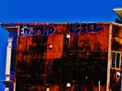 Workers painting the exterior walls of a building under clear skies.