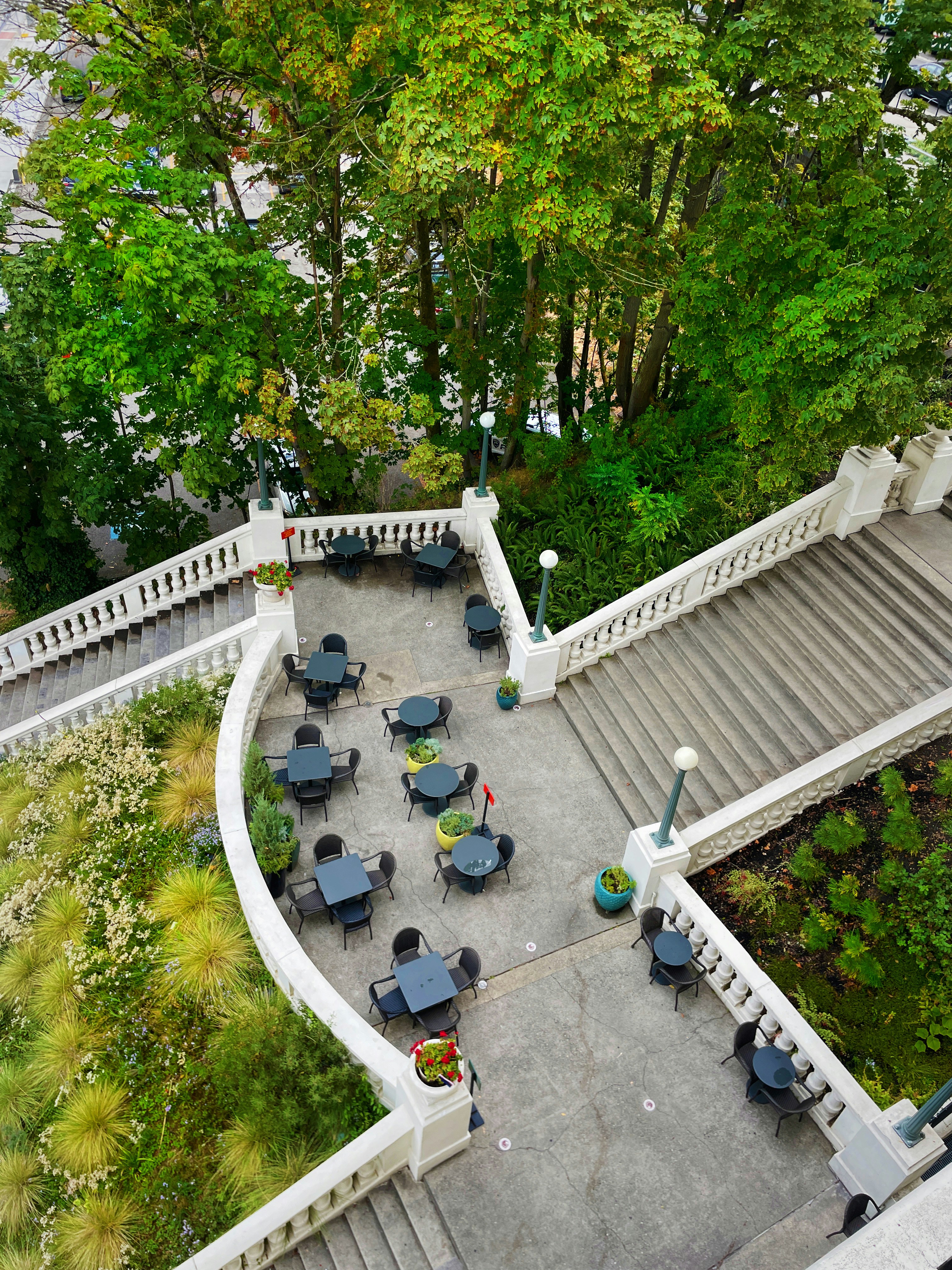 Outdoor patio with seating area surrounded by flowers and greenery
