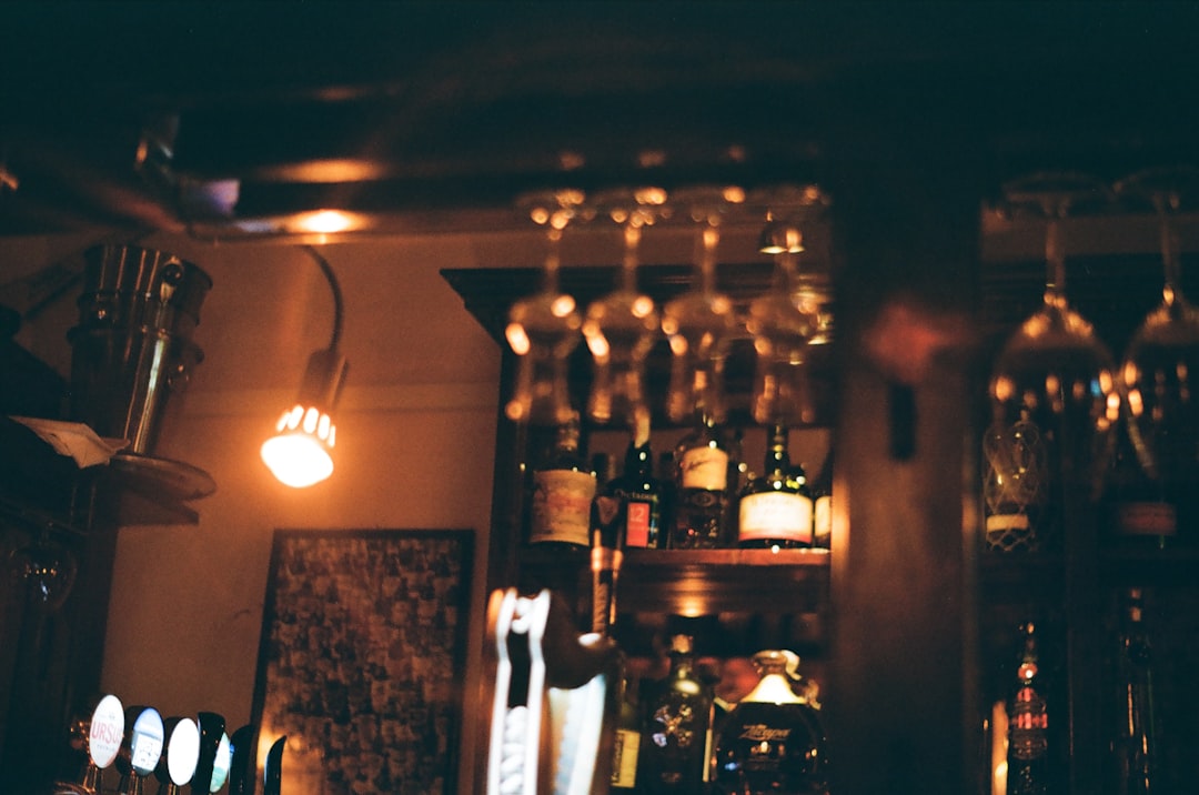 a wine rack filled with lots of bottles and glasses, Happy Hour! (Fujifilm 200)