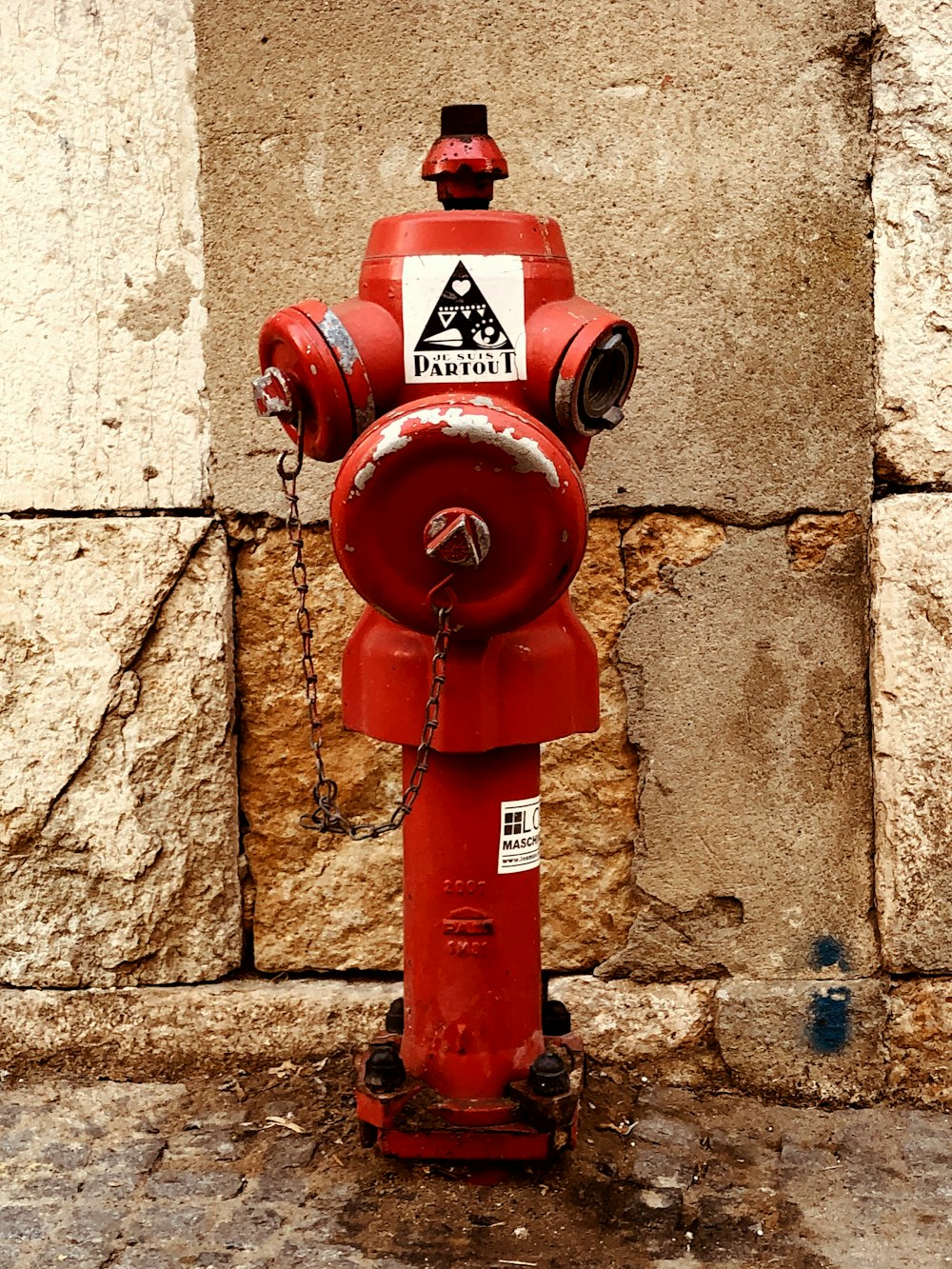 a red fire hydrant sitting next to a stone wall