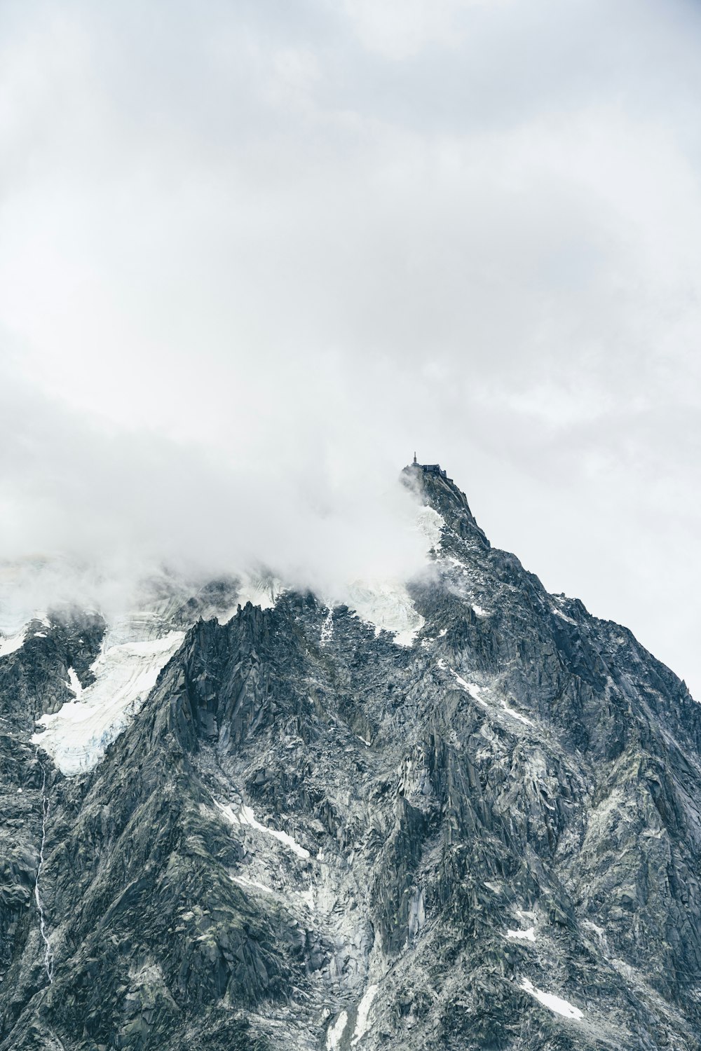 a very tall mountain covered in snow under a cloudy sky