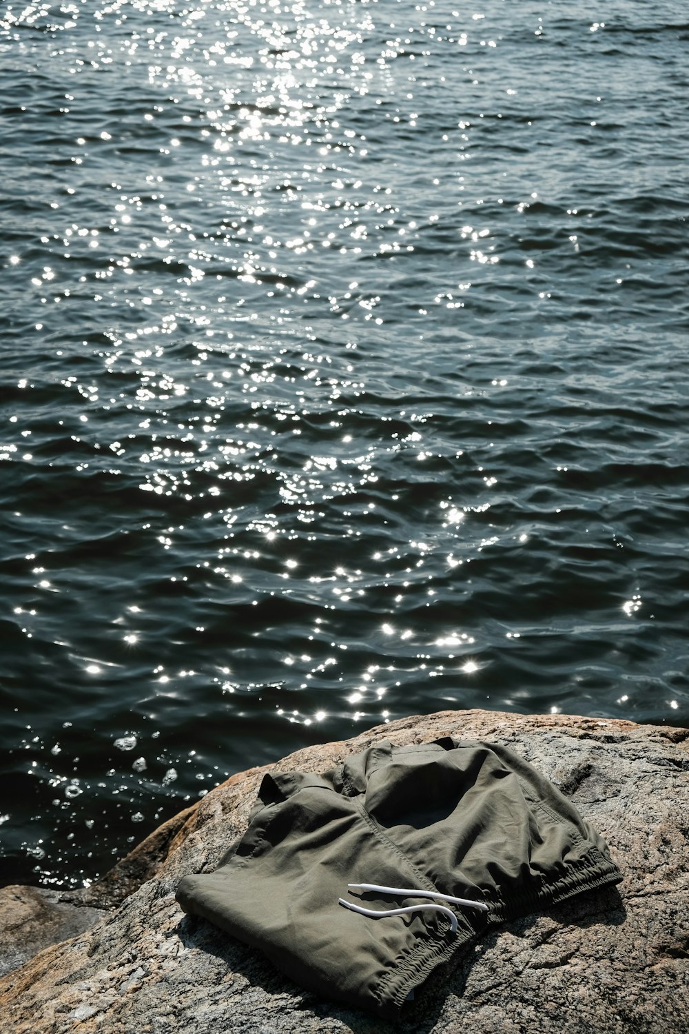 a pair of shorts sitting on top of a rock next to a body of water