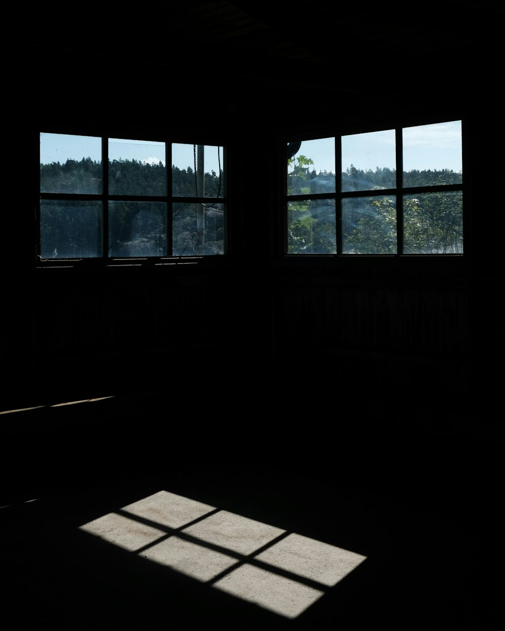 a dark room with two windows and the sun shining in