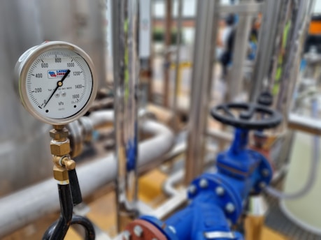 Close-up of a precision flow meter installed in an industrial pipeline, highlighting its digital display and robust metal casing.