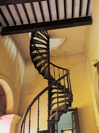 Hand-forged wrought iron staircase railing inside a warm, rustic interior.