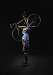 A rider wearing a helmet and gloves holding Ubco bike gear next to their bike.