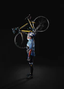 A rider wearing a helmet and gloves holding Ubco bike gear next to their bike.