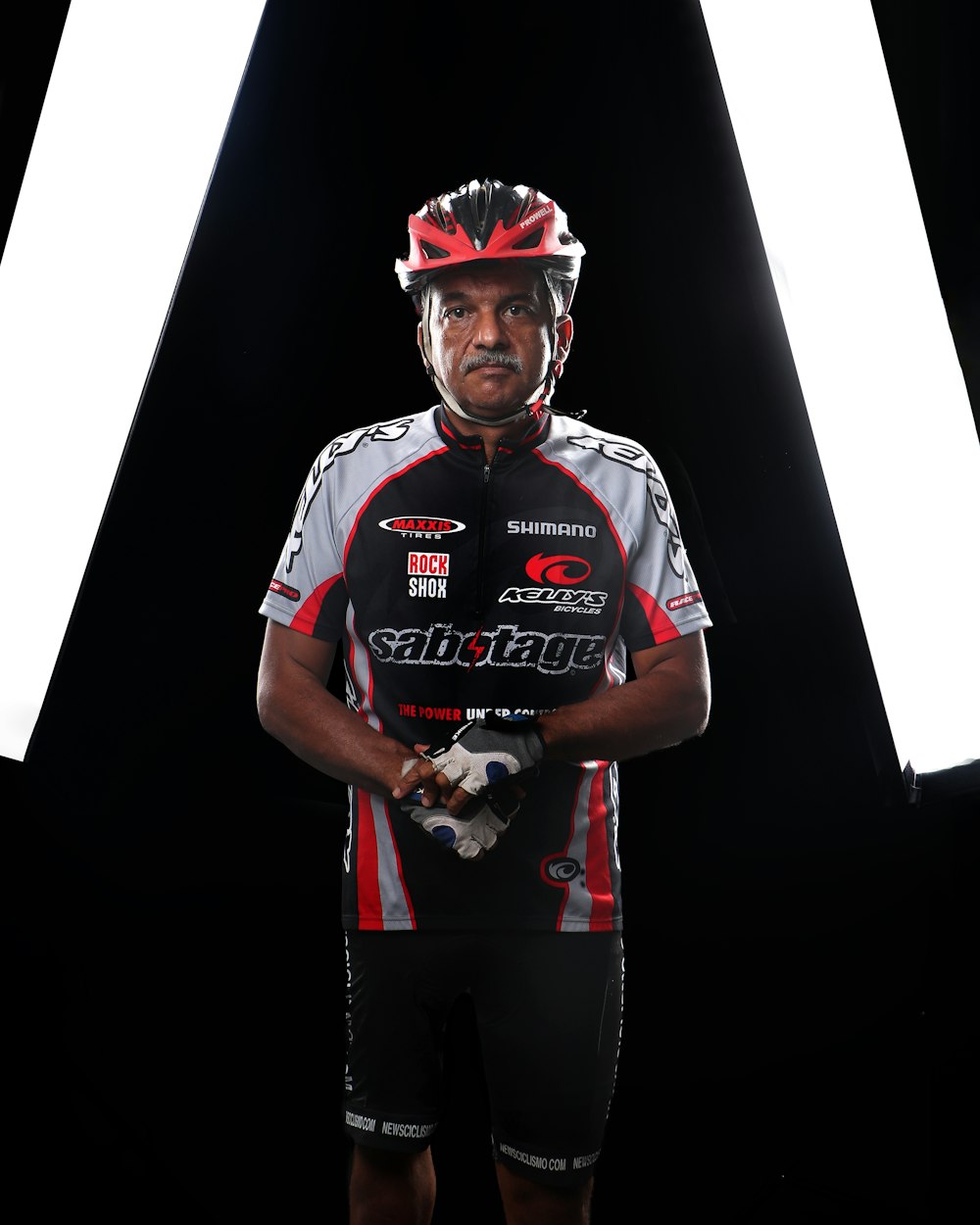 a man with a helmet and gloves standing in front of a black background