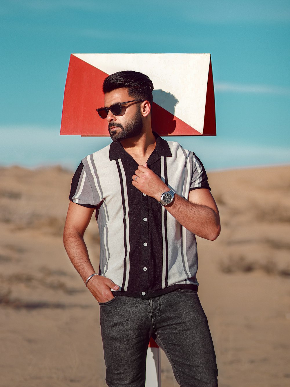 a man standing on a beach with a red and white box on his head