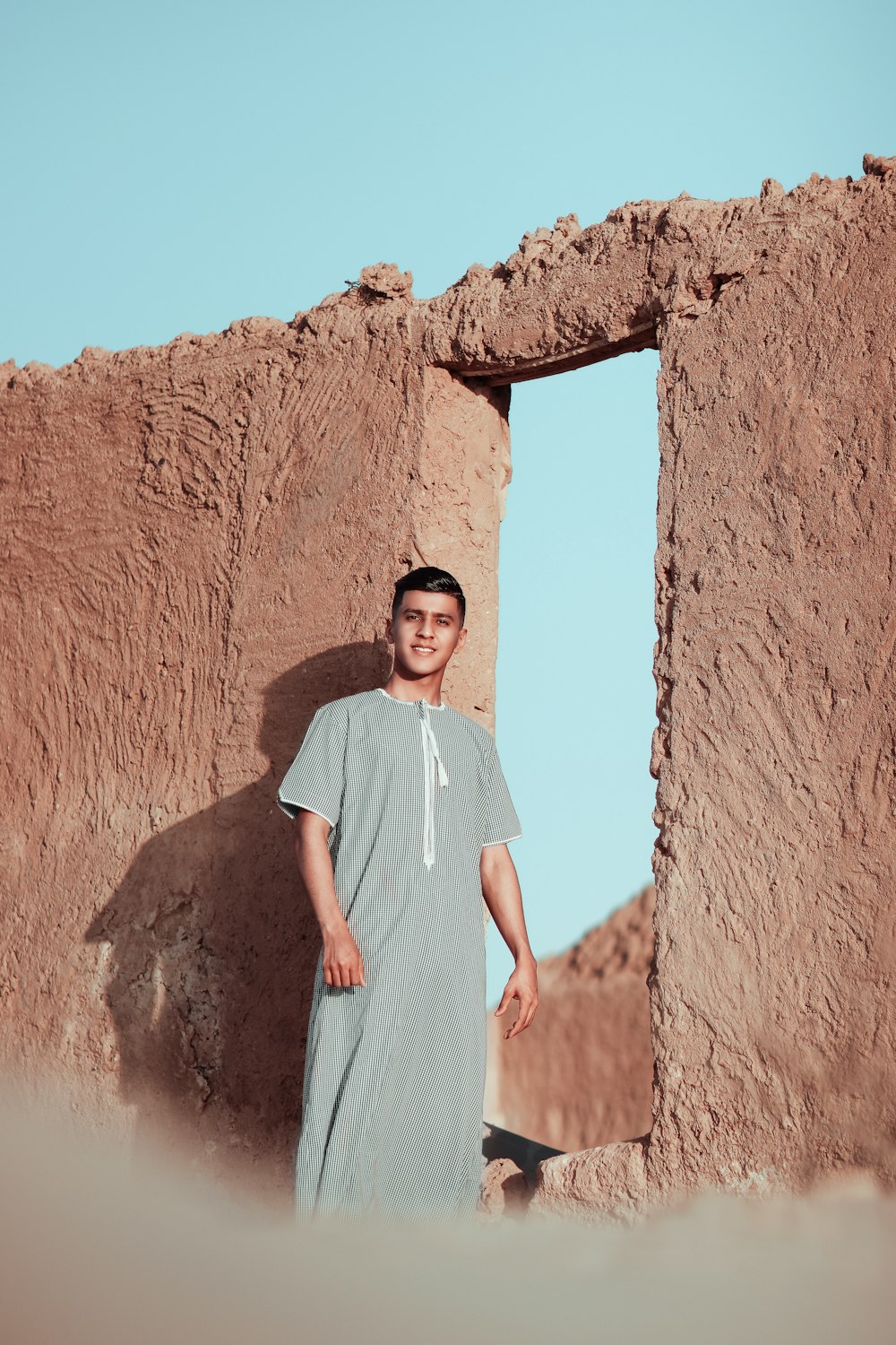 a man standing in front of a adobe building