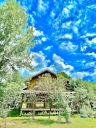 A cozy house surrounded by a green garden under a clear sky