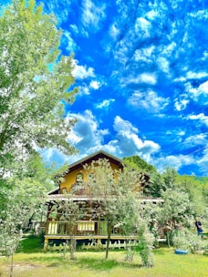 Front view of a cozy two-story house with a well-kept garden and bright blue sky.