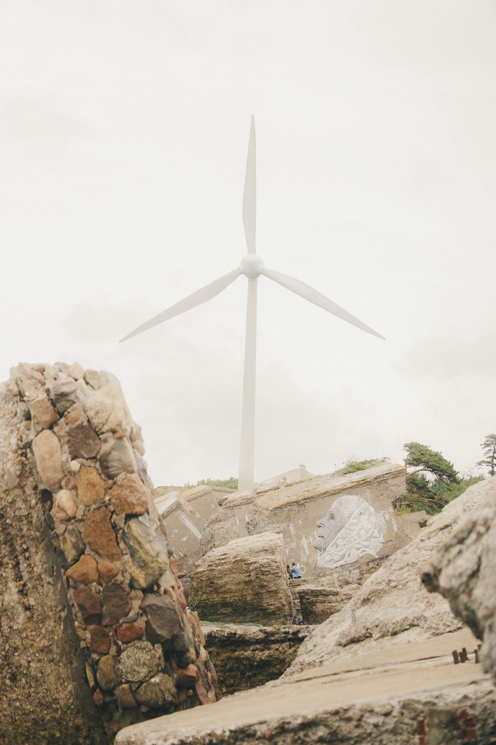 a wind turbine towering over a stone wall