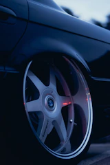 Hands applying an M Sport sticker gently onto a BMW wheel rim under natural daylight.