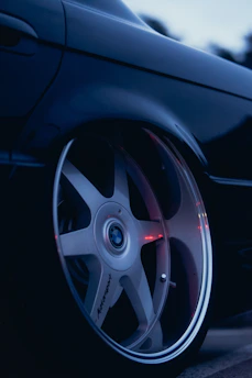 Hands applying an M Sport sticker gently onto a BMW wheel rim under natural daylight.