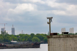 A sturdy security camera mounted high overlooking a bustling construction site at dawn.