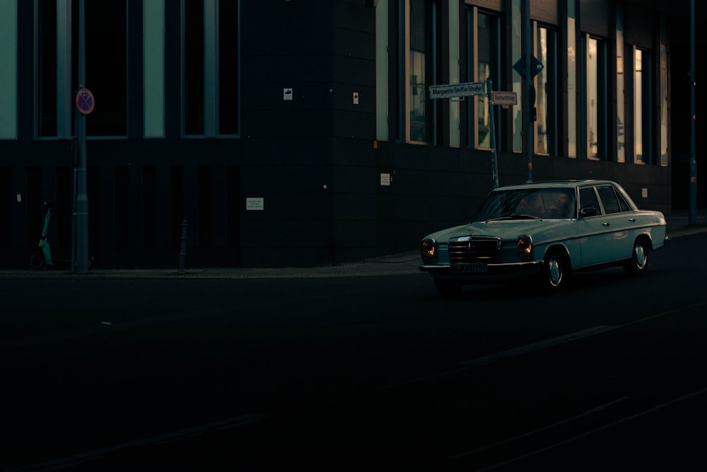 a car driving down a street next to a tall building