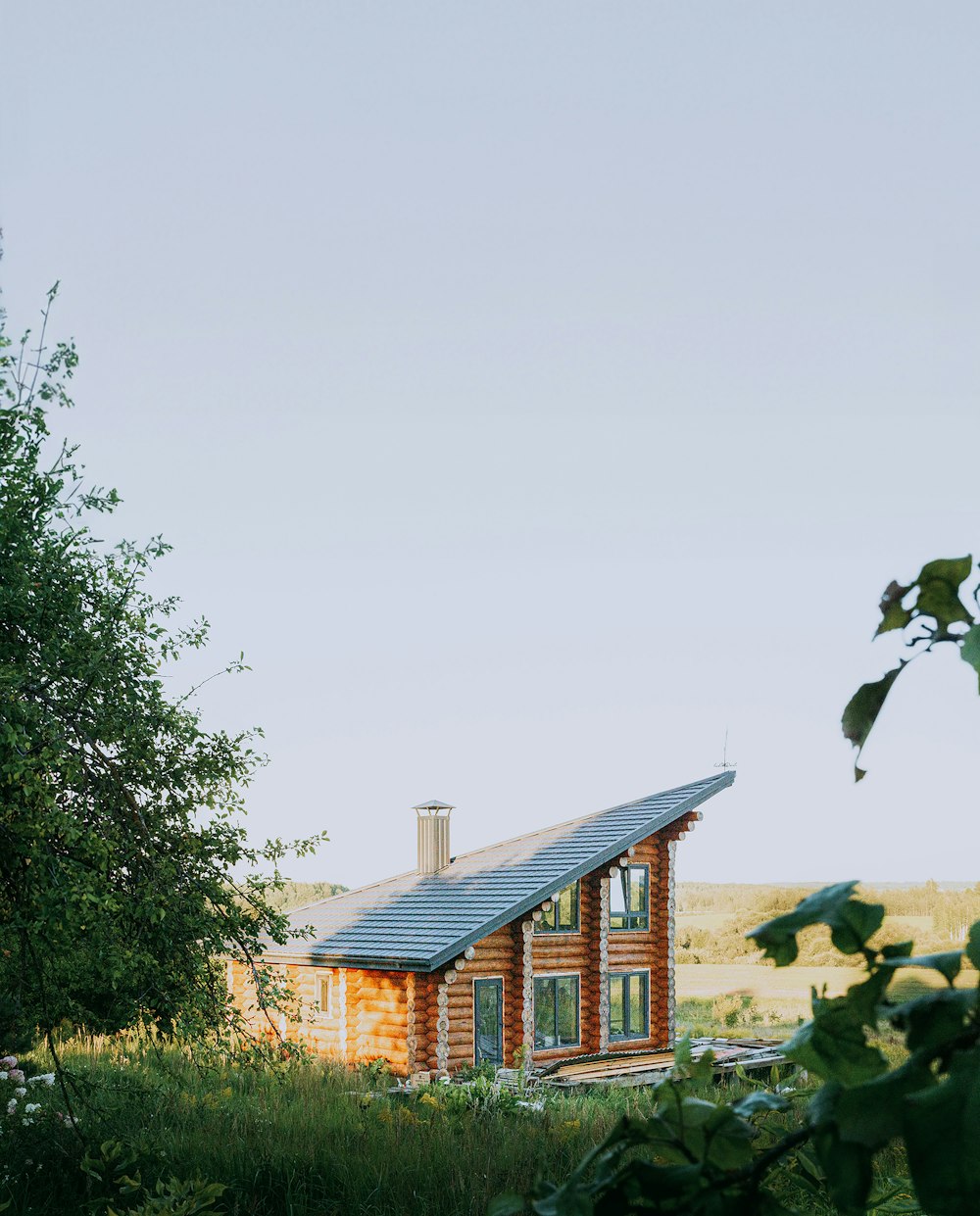 a small wooden cabin in a field with trees