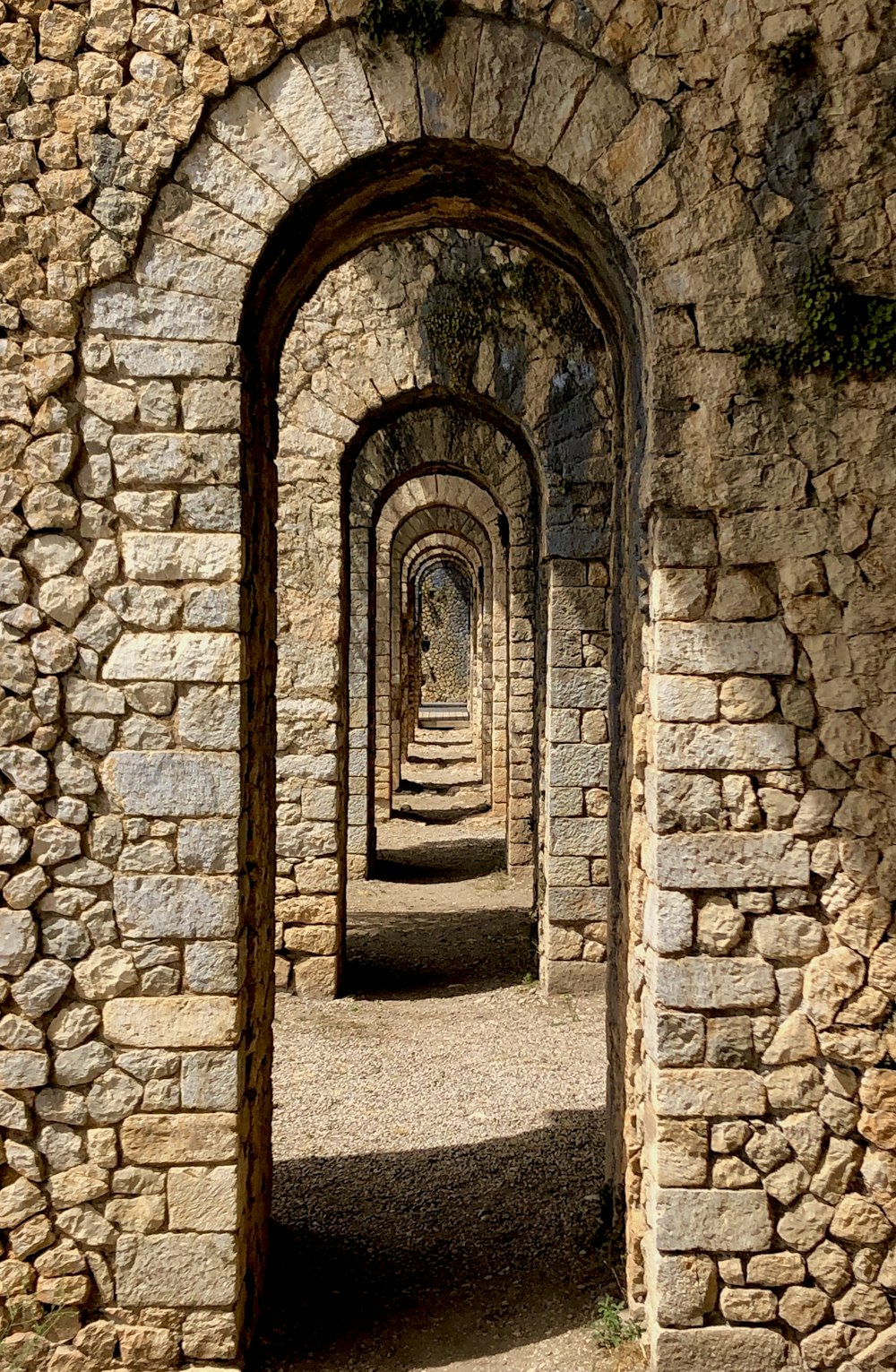 a stone tunnel with a walkway between it
