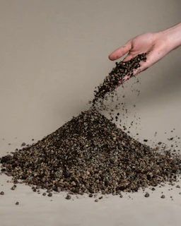 Close-up of gravel being spread evenly over a driveway surface by skilled hands