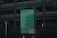 A green signboard features handwritten text that reads 'Sometimes it's alright not to be alright.' Below is information about a helpline, Samaritans, with a contact number and website. The background includes a dark, industrial-looking building with multiple floors and a metal fence.
