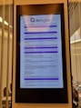 A digital display in a modern setting shows an agenda for a conference or workshop related to agile product development. The schedule includes various sessions, case studies, and coffee breaks, with timings from 9:00 to 16:45. The display has a header labeled 'Product inAgile' and sections are highlighted in purple.