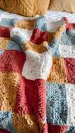 a crocheted blanket is laying on a bed