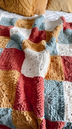 a crocheted blanket is laying on a bed