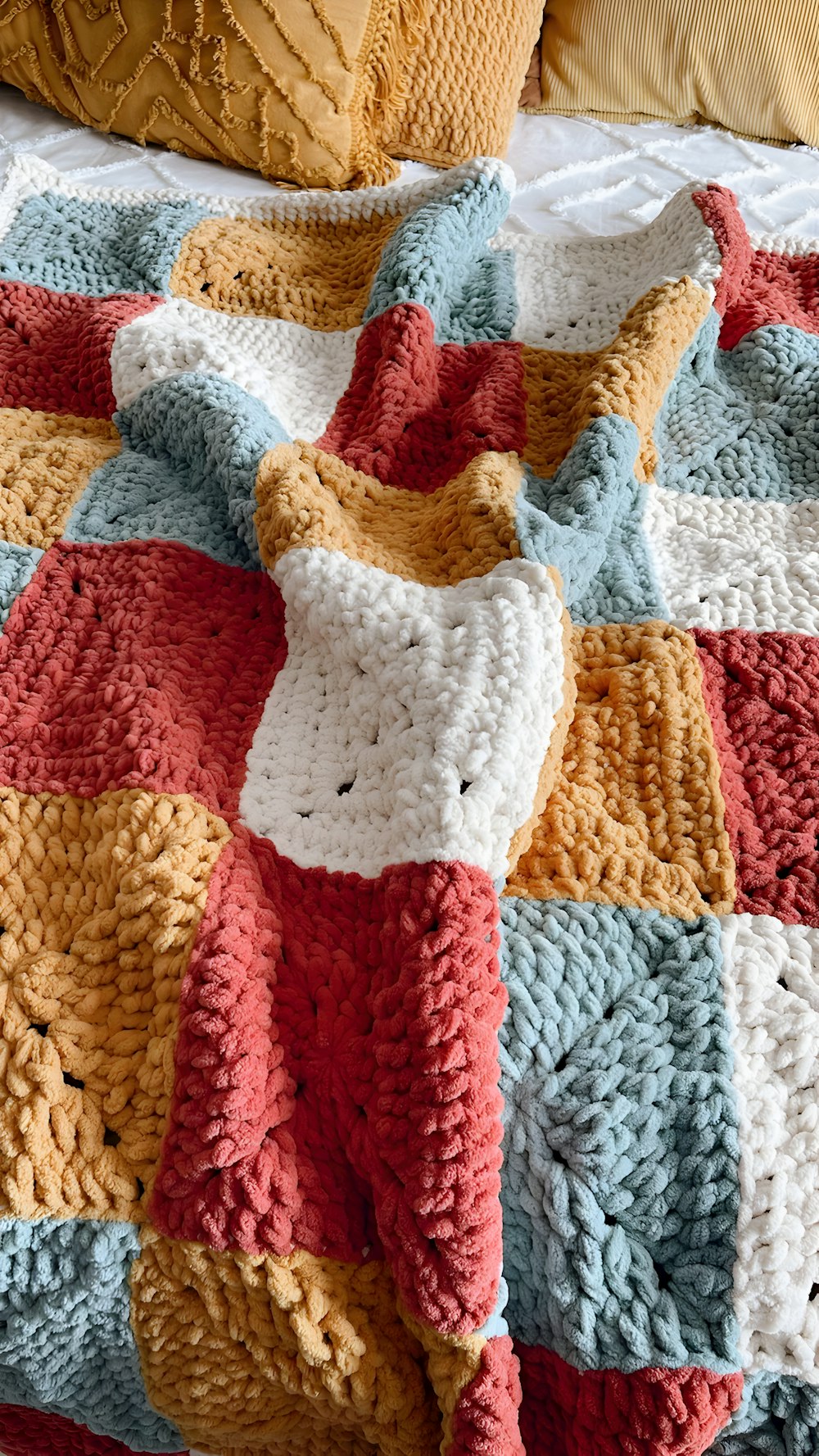 a crocheted blanket is laying on a bed
