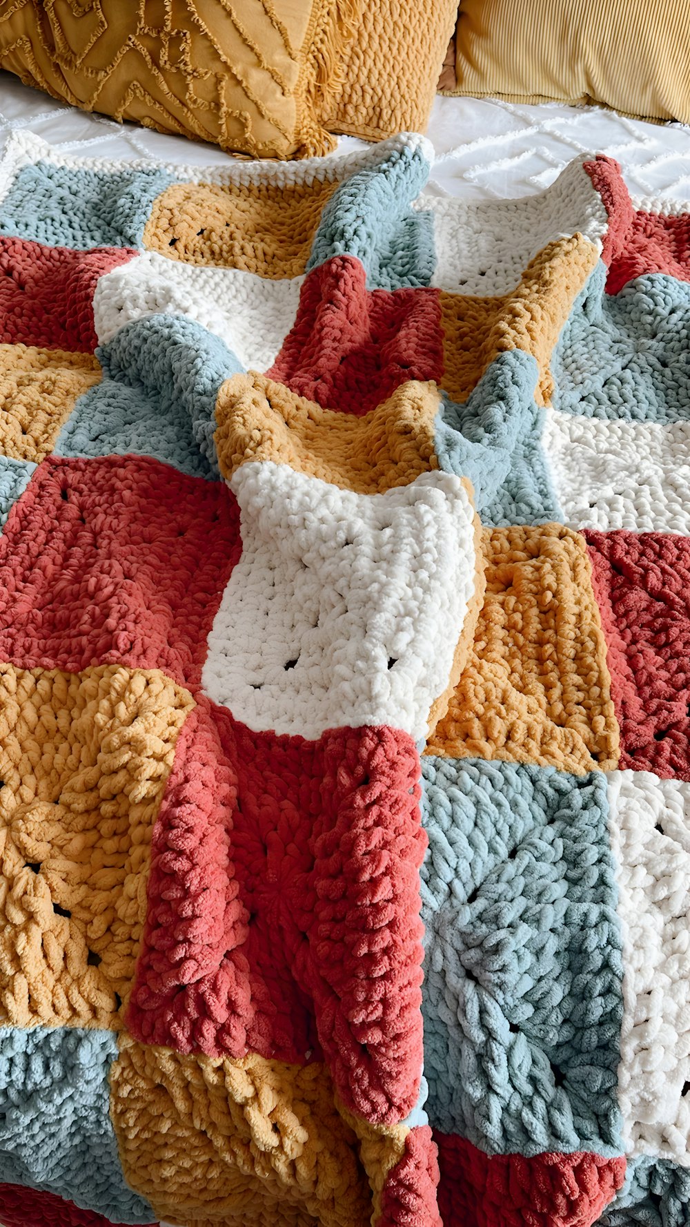 une couverture crochetée est allongée sur un lit