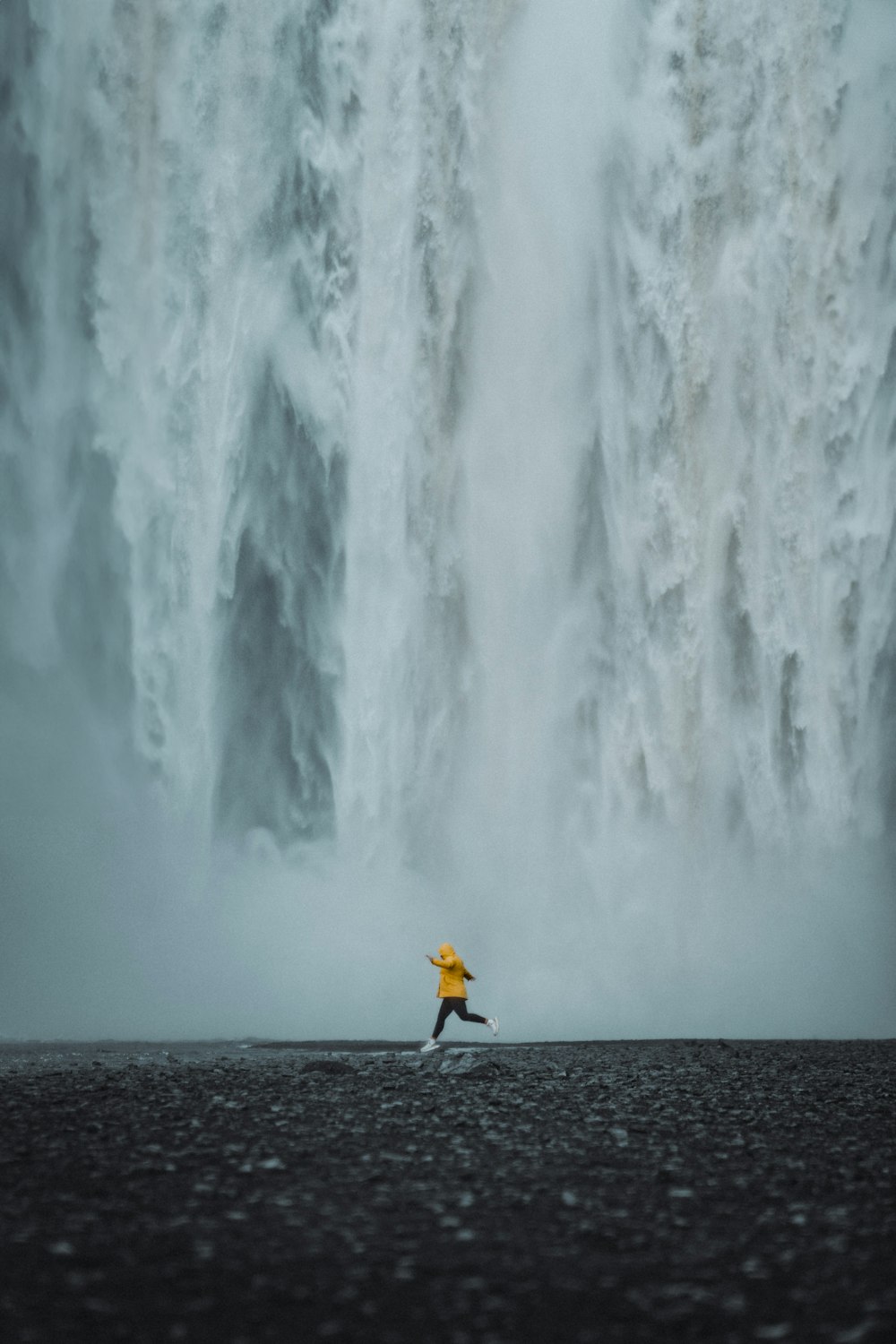 Una persona parada frente a una gran cascada