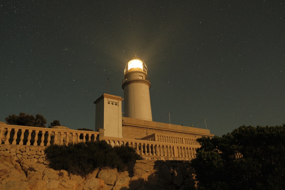 a lighthouse on top of a cliff under a night sky